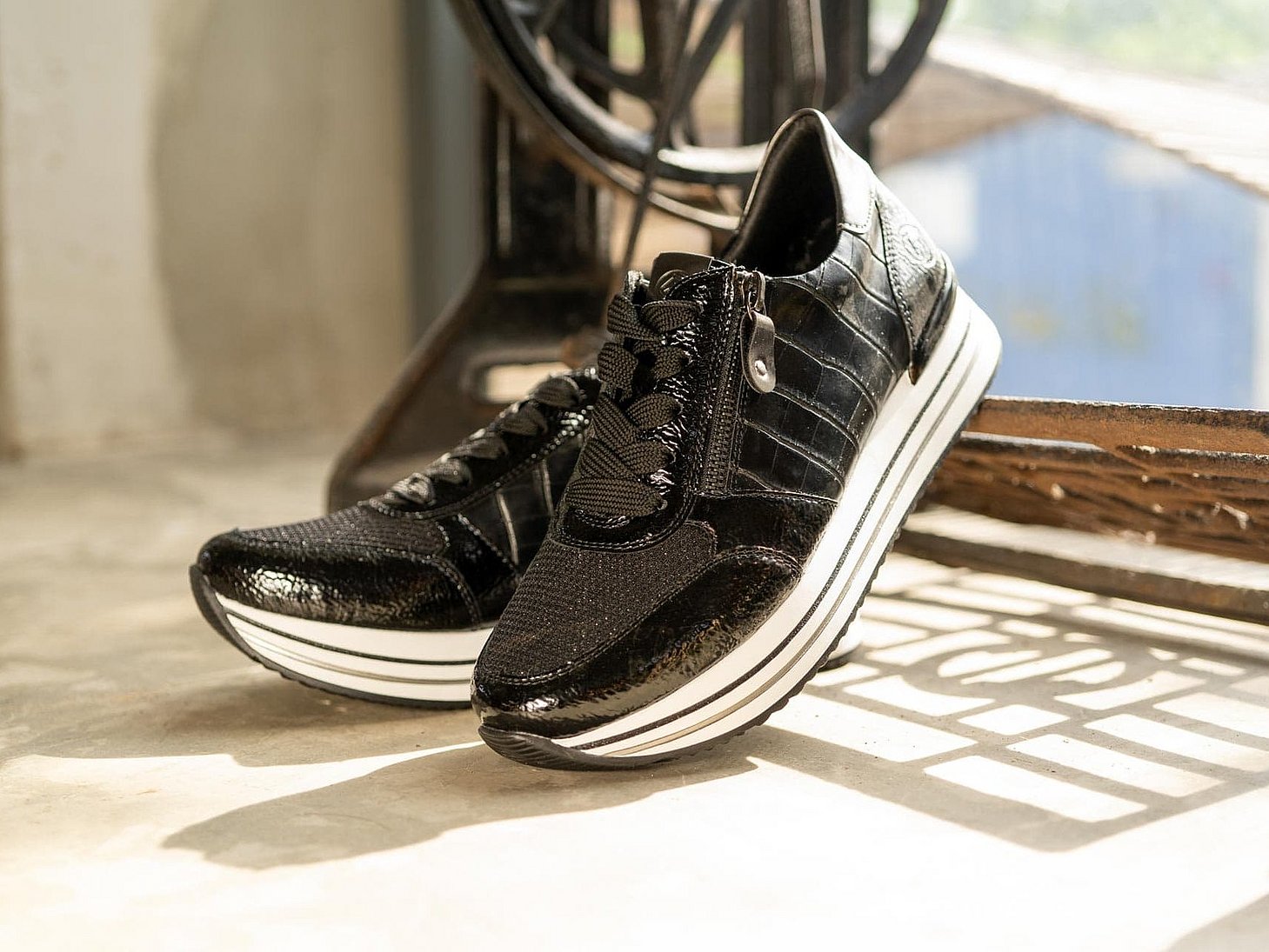Schwarze Sneaker aus Kunstlack mit Reißverschluss und Schnürung und Wechselfußbett.