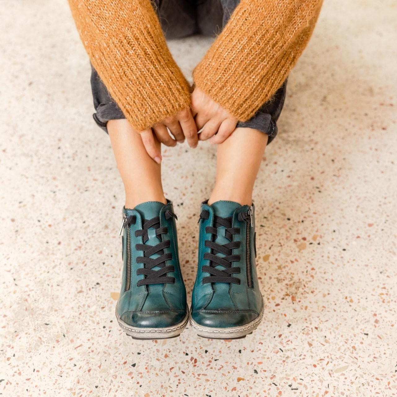 Blaue Schnürschuhe leicht wärmend aus Glattleder mit Reißverschluss und Schnürung und Wechselfußbett. Passend zu den Schuhen trägt die Frau einen ockerfarbenen Pullover und eine dunkle Jeans.