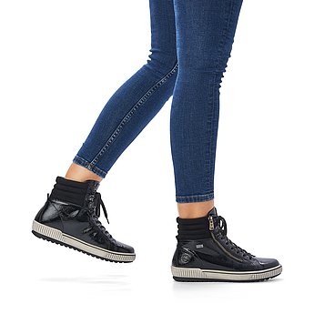 Schwarze Stiefeletten leicht wärmend aus Lacklederimitat mit Reißverschluss und Schnürung, wasserabweisendem Remonte TEX und Wechselfußbett. Schuhe am Fuß.