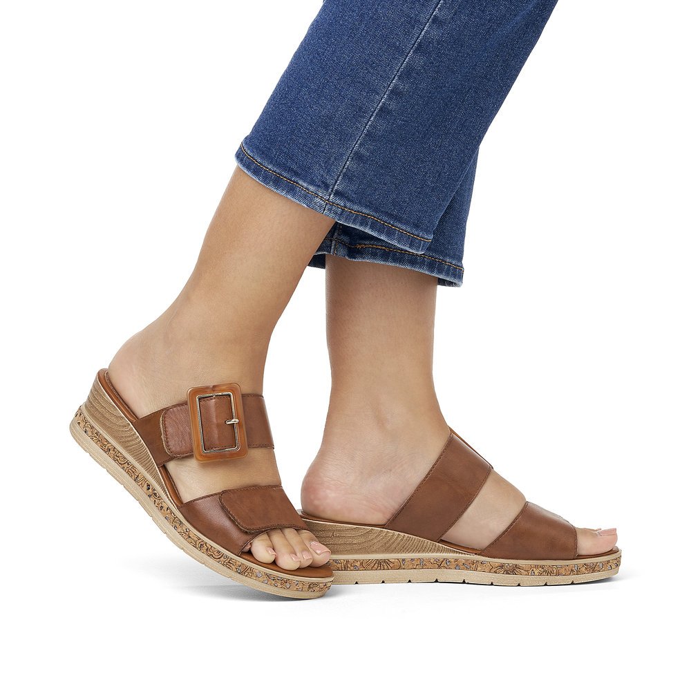 Coffee brown remonte women´s mules D3068-24 with a hook and loop fastener. Shoe on foot.