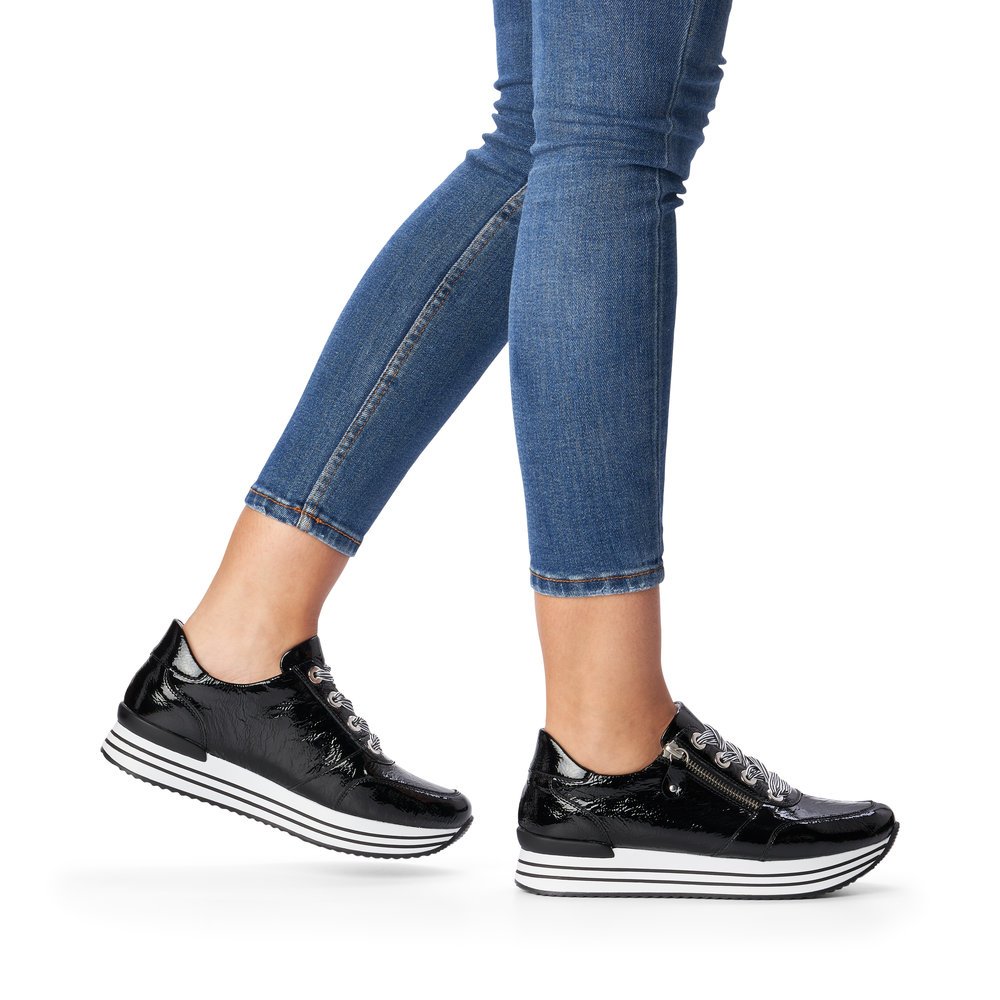 Black remonte women´s sneakers D1302-02 with zipper and stripe pattern. Shoe on foot.